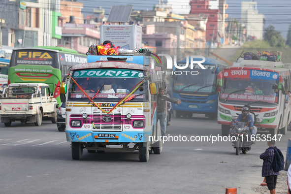 The staff of a passenger bus calls for passengers as it departs from Kathmandu, Nepal, on October 10, 2024. Thousands of people leave the Ne...