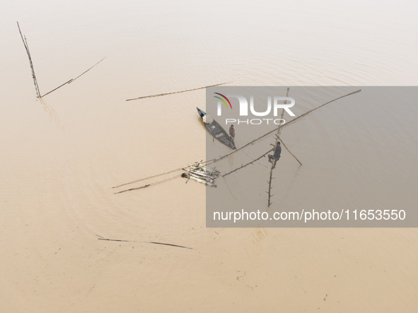 Fishermen create fishing grounds with bamboo and catch various types of fish with nets from the flooded open ghat in Jhenaigati Upazila of S...