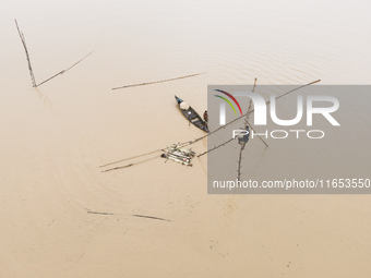 Fishermen create fishing grounds with bamboo and catch various types of fish with nets from the flooded open ghat in Jhenaigati Upazila of S...