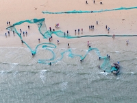 Fishermen cast long nets to catch seafood at the shore of the Yellow Sea in Lingshan Bay, West Coast New District, in Qingdao, China, on Oct...