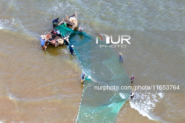 Fishermen cast long nets to catch seafood at the shore of the Yellow Sea in Lingshan Bay, West Coast New District, in Qingdao, China, on Oct...