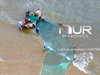 Fishermen cast long nets to catch seafood at the shore of the Yellow Sea in Lingshan Bay, West Coast New District, in Qingdao, China, on Oct...