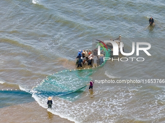 Fishermen cast long nets to catch seafood at the shore of the Yellow Sea in Lingshan Bay, West Coast New District, in Qingdao, China, on Oct...