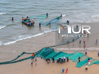 Fishermen cast long nets to catch seafood at the shore of the Yellow Sea in Lingshan Bay, West Coast New District, in Qingdao, China, on Oct...