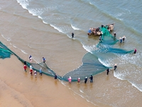 Fishermen cast long nets to catch seafood at the shore of the Yellow Sea in Lingshan Bay, West Coast New District, in Qingdao, China, on Oct...