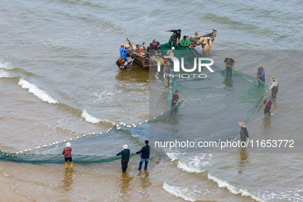 Fishermen cast long nets to catch seafood at the shore of the Yellow Sea in Lingshan Bay, West Coast New District, in Qingdao, China, on Oct...