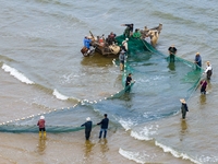 Fishermen cast long nets to catch seafood at the shore of the Yellow Sea in Lingshan Bay, West Coast New District, in Qingdao, China, on Oct...