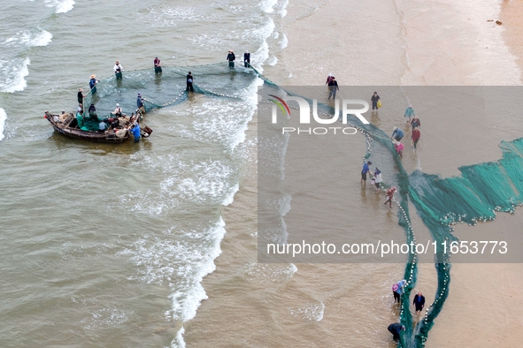 Fishermen cast long nets to catch seafood at the shore of the Yellow Sea in Lingshan Bay, West Coast New District, in Qingdao, China, on Oct...