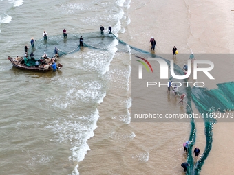 Fishermen cast long nets to catch seafood at the shore of the Yellow Sea in Lingshan Bay, West Coast New District, in Qingdao, China, on Oct...