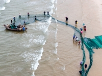 Fishermen cast long nets to catch seafood at the shore of the Yellow Sea in Lingshan Bay, West Coast New District, in Qingdao, China, on Oct...