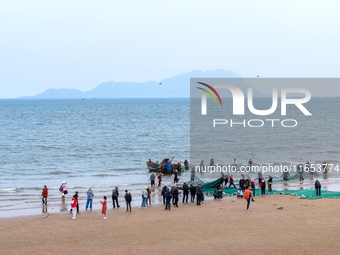 Fishermen cast long nets to catch seafood at the shore of the Yellow Sea in Lingshan Bay, West Coast New District, in Qingdao, China, on Oct...