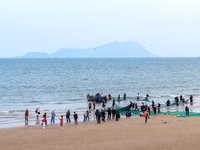 Fishermen cast long nets to catch seafood at the shore of the Yellow Sea in Lingshan Bay, West Coast New District, in Qingdao, China, on Oct...