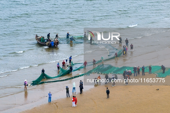 Fishermen cast long nets to catch seafood at the shore of the Yellow Sea in Lingshan Bay, West Coast New District, in Qingdao, China, on Oct...