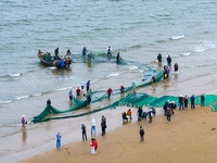 Fishermen cast long nets to catch seafood at the shore of the Yellow Sea in Lingshan Bay, West Coast New District, in Qingdao, China, on Oct...