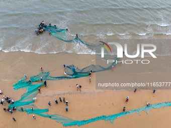 Fishermen cast long nets to catch seafood at the shore of the Yellow Sea in Lingshan Bay, West Coast New District, in Qingdao, China, on Oct...