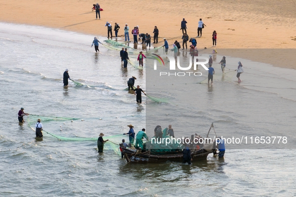 Fishermen cast long nets to catch seafood at the shore of the Yellow Sea in Lingshan Bay, West Coast New District, in Qingdao, China, on Oct...