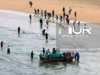 Fishermen cast long nets to catch seafood at the shore of the Yellow Sea in Lingshan Bay, West Coast New District, in Qingdao, China, on Oct...