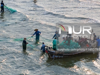 Fishermen cast long nets to catch seafood at the shore of the Yellow Sea in Lingshan Bay, West Coast New District, in Qingdao, China, on Oct...