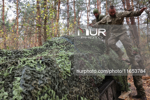 Soldiers of Ukraine's 154th Separate Mechanized Brigade man a 2S1 Gvozdika self-propelled howitzer covered with camouflage netting at positi...