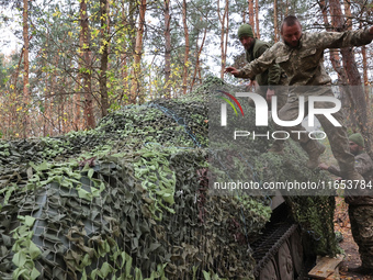 Soldiers of Ukraine's 154th Separate Mechanized Brigade man a 2S1 Gvozdika self-propelled howitzer covered with camouflage netting at positi...