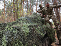 Soldiers of Ukraine's 154th Separate Mechanized Brigade man a 2S1 Gvozdika self-propelled howitzer covered with camouflage netting at positi...