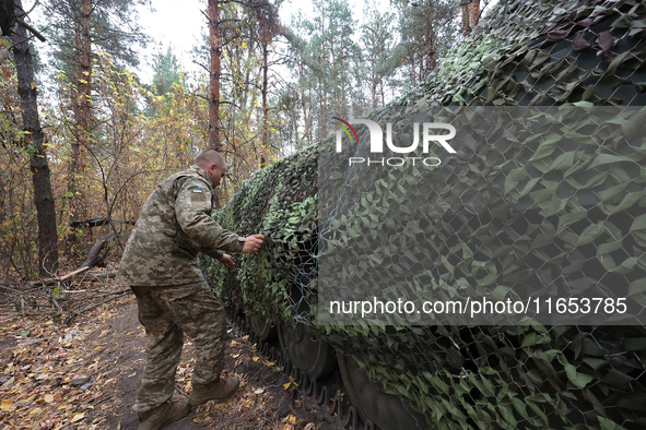 A soldier of Ukraine's 154th Separate Mechanized Brigade mans a 2S1 Gvozdika self-propelled howitzer covered with camouflage netting at posi...