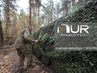 A soldier of Ukraine's 154th Separate Mechanized Brigade mans a 2S1 Gvozdika self-propelled howitzer covered with camouflage netting at posi...