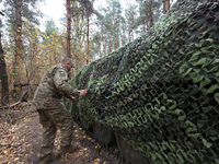 A soldier of Ukraine's 154th Separate Mechanized Brigade mans a 2S1 Gvozdika self-propelled howitzer covered with camouflage netting at posi...