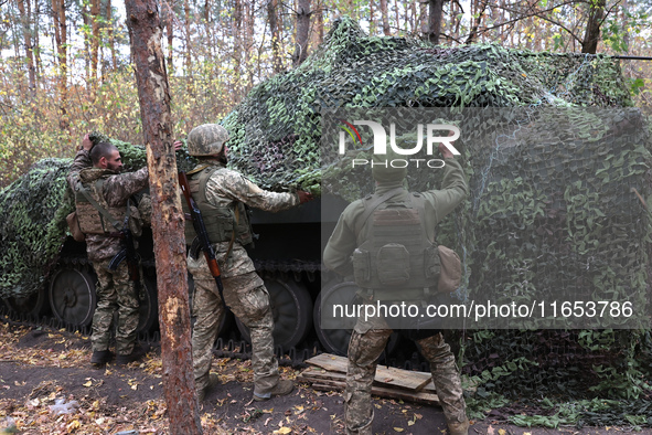 Soldiers of Ukraine's 154th Separate Mechanized Brigade man a 2S1 Gvozdika self-propelled howitzer covered with camouflage netting at positi...