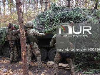 Soldiers of Ukraine's 154th Separate Mechanized Brigade man a 2S1 Gvozdika self-propelled howitzer covered with camouflage netting at positi...