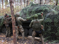 Soldiers of Ukraine's 154th Separate Mechanized Brigade man a 2S1 Gvozdika self-propelled howitzer covered with camouflage netting at positi...