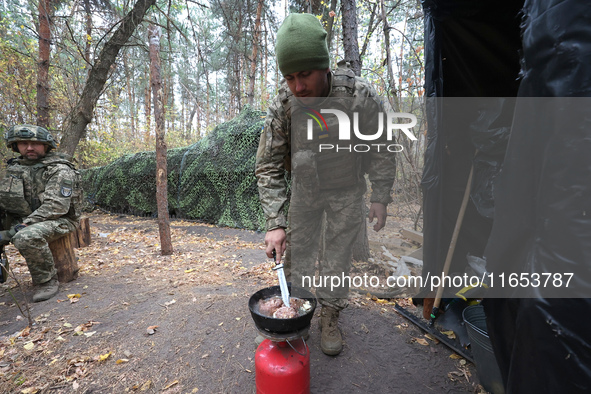 A soldier from the 2S1 Gvozdika self-propelled howitzer crew of Ukraine's 154th Separate Mechanized Brigade cooks over a gas cylinder at pos...