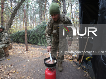 A soldier from the 2S1 Gvozdika self-propelled howitzer crew of Ukraine's 154th Separate Mechanized Brigade cooks over a gas cylinder at pos...