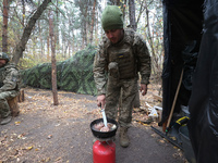 A soldier from the 2S1 Gvozdika self-propelled howitzer crew of Ukraine's 154th Separate Mechanized Brigade cooks over a gas cylinder at pos...