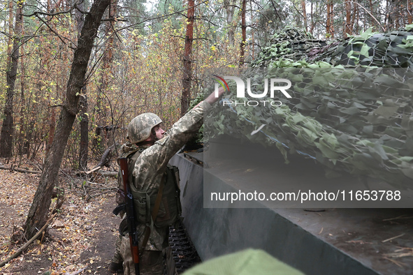 A soldier of Ukraine's 154th Separate Mechanized Brigade mans a 2S1 Gvozdika self-propelled howitzer covered with camouflage netting at posi...