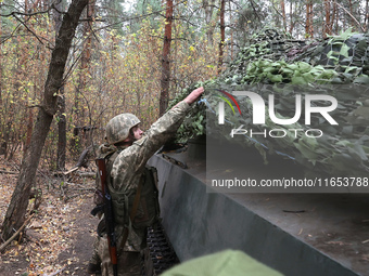 A soldier of Ukraine's 154th Separate Mechanized Brigade mans a 2S1 Gvozdika self-propelled howitzer covered with camouflage netting at posi...