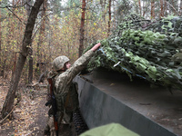 A soldier of Ukraine's 154th Separate Mechanized Brigade mans a 2S1 Gvozdika self-propelled howitzer covered with camouflage netting at posi...