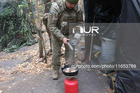 A soldier from the 2S1 Gvozdika self-propelled howitzer crew of Ukraine's 154th Separate Mechanized Brigade cooks over a gas cylinder at pos...