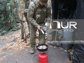 A soldier from the 2S1 Gvozdika self-propelled howitzer crew of Ukraine's 154th Separate Mechanized Brigade cooks over a gas cylinder at pos...