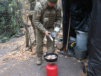 A soldier from the 2S1 Gvozdika self-propelled howitzer crew of Ukraine's 154th Separate Mechanized Brigade cooks over a gas cylinder at pos...