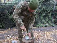 A soldier from the 2S1 Gvozdika self-propelled howitzer crew of Ukraine's 154th Separate Mechanized Brigade opens a tin can with a knife at...