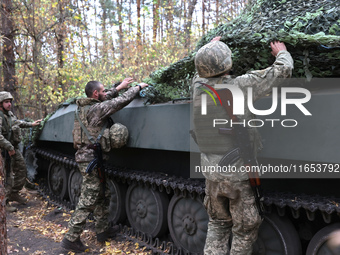 Soldiers of Ukraine's 154th Separate Mechanized Brigade man a 2S1 Gvozdika self-propelled howitzer covered with camouflage netting at positi...