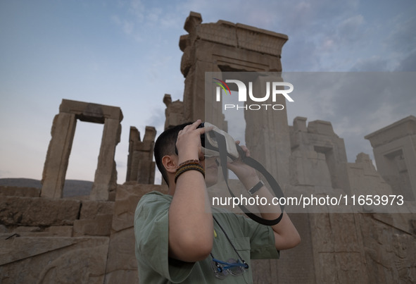 An Iranian young boy uses VR glasses while visiting the Persepolis historical site near the city of Shiraz in Fars province, about 932 km (5...