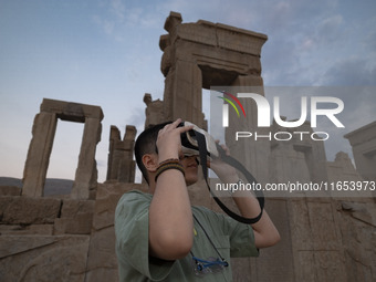 An Iranian young boy uses VR glasses while visiting the Persepolis historical site near the city of Shiraz in Fars province, about 932 km (5...