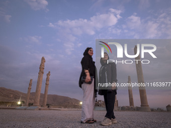 Two young Iranian women pose for a photograph while visiting the Persepolis historical site near Shiraz, Iran, on October 9, 2024.  (