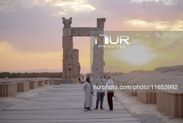 An Iranian guide speaks with an Iranian couple visiting the Persepolis historical site near the city of Shiraz in Fars province, about 932 k...