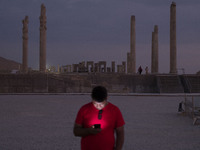 An Iranian man uses his cellphone while visiting the Persepolis historical site near the city of Shiraz in Fars province, about 932 km (579...