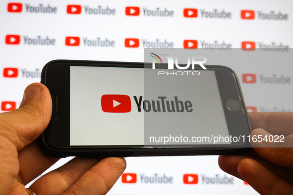 A man holding a smartphone with a Youtube logo and small YouTube logos displayed on a screen are seen in L’Aquila, Italy, on October 9th, 20...