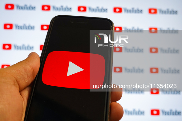 A man holding a smartphone with a Youtube logo and small YouTube logos displayed on a screen are seen in L’Aquila, Italy, on October 9th, 20...