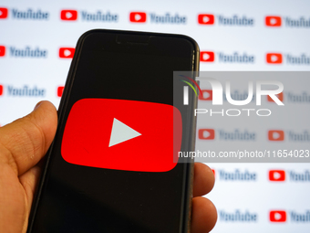 A man holding a smartphone with a Youtube logo and small YouTube logos displayed on a screen are seen in L’Aquila, Italy, on October 9th, 20...